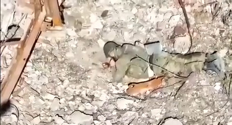 Soldier laying prone puts grenade to face and pulls pin