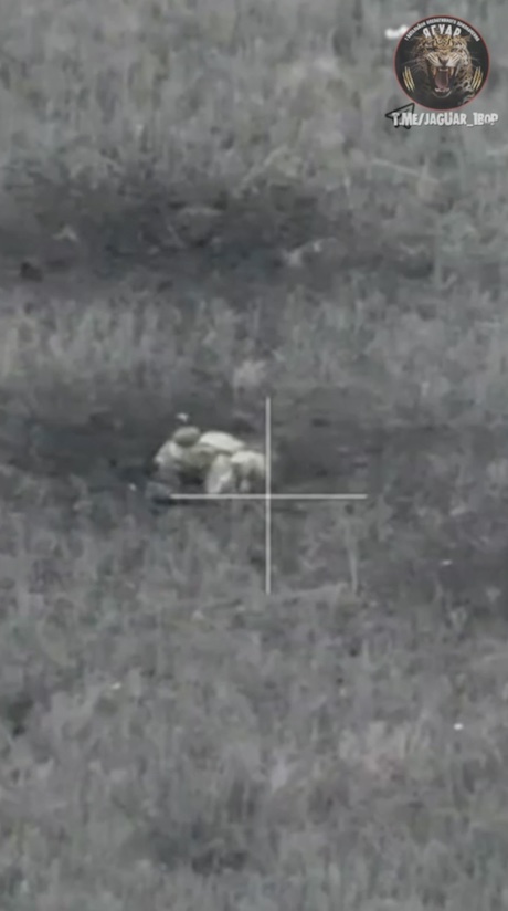 Russian is seen crouched in the middle of a field near motorcycle that broke. Unwilling to suffer from drone attacks, he blows up grenade to his face