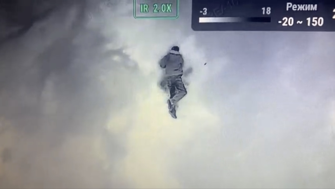 Unarmed Russian with no helmet seen from above on empty surface pulls pin on his grenade and puts it under his chest