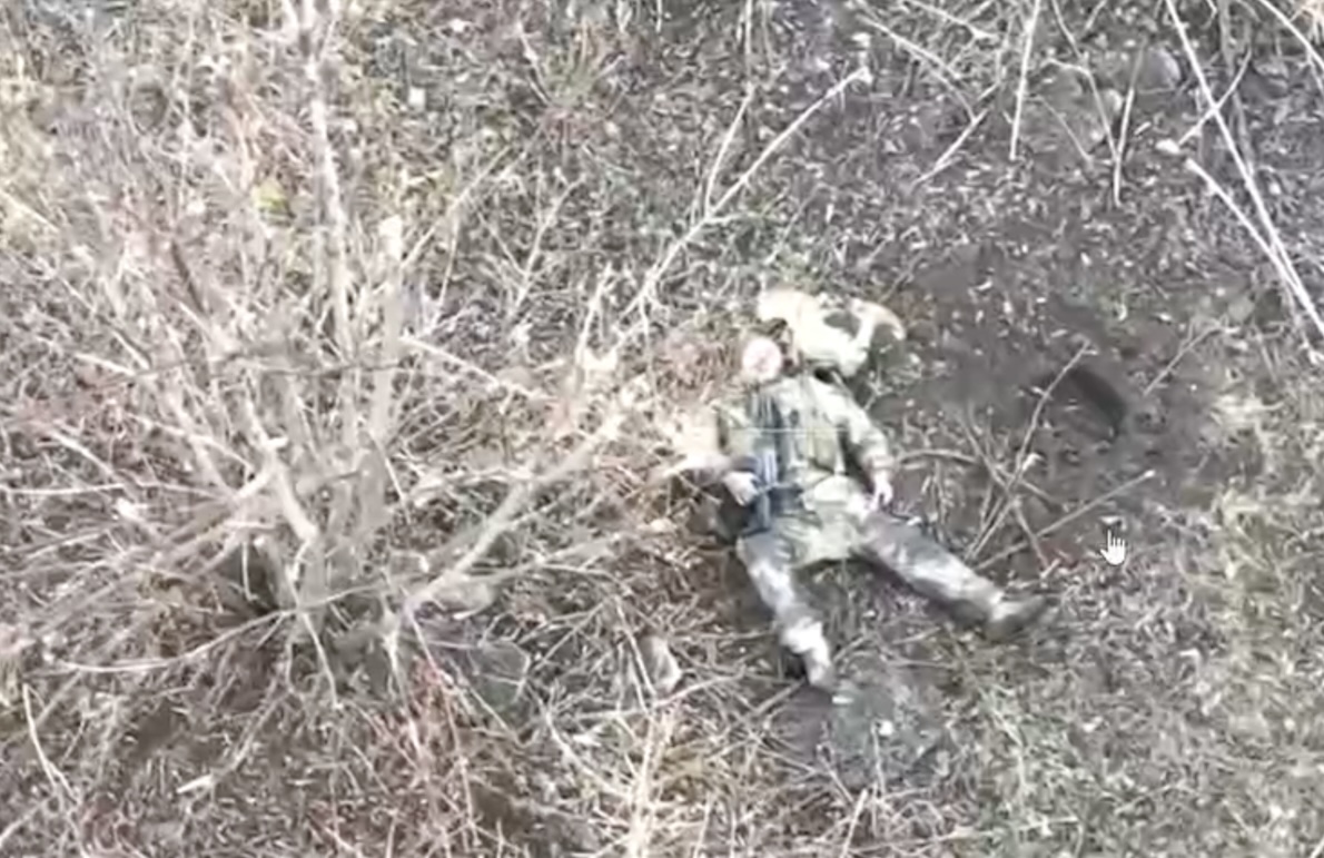 Russian is lying face up, shoots from his AK pointed at his face moment before drone dropped grenade landed his chest
