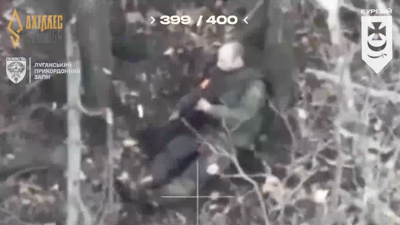 Russian sitting between two trees is under drone attack, his leg is injured. He crawls around, loses his helmet, grabs rifle and shoots himself