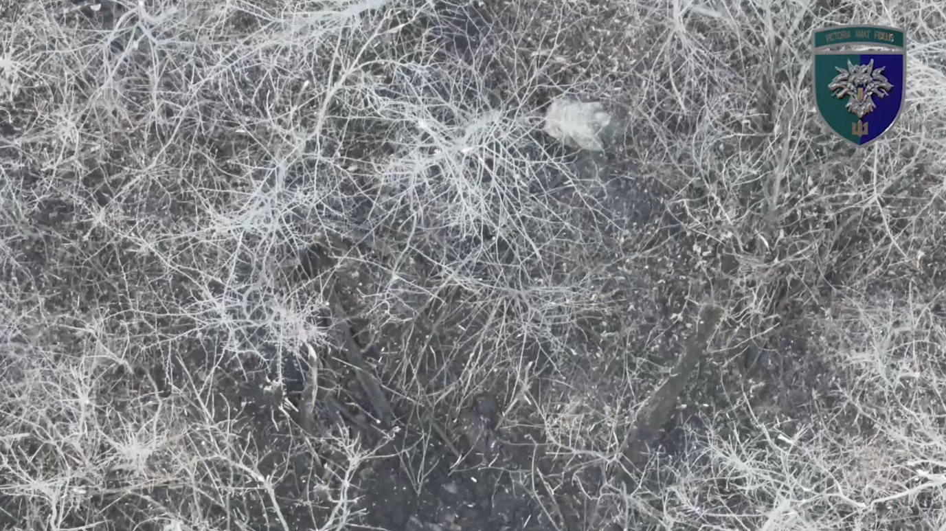 Russian is crawling among fallen trees, receives close drone drop. He first tries his AK and proceeds with shooting himself