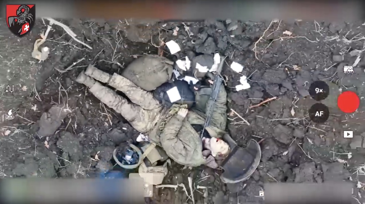 Russian soldier is seen lying dead in what looks like suicide scene. His AK near his chin, his finger still on its trigger, and his belongings including phone carefully put into his helmet