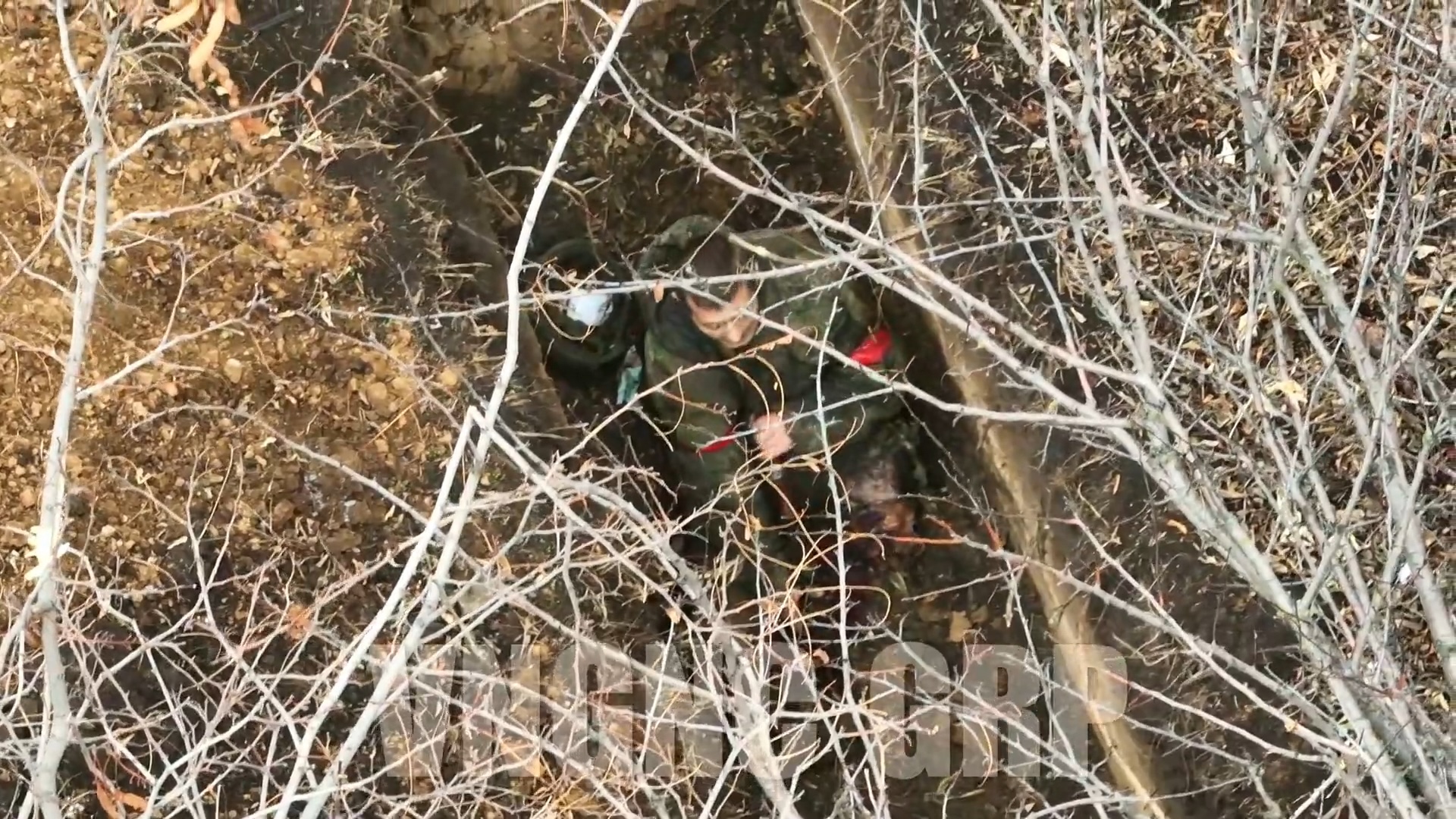 Russian in rectangular foxhole is struck by drone drop, his leg flying off into the bushes. He makes eye contact with the drone, inspects his wounds for a few moments, then grabs his AK and shoots himself on full auto