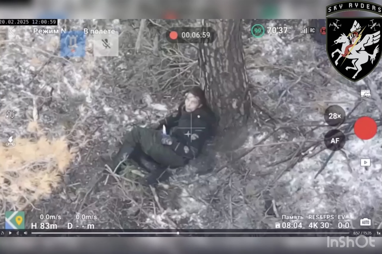 Unequipped Russian soldier is sitting under the tree with a knife in his hand, makes eye contact with drone operator and proceeds with cutting own throat