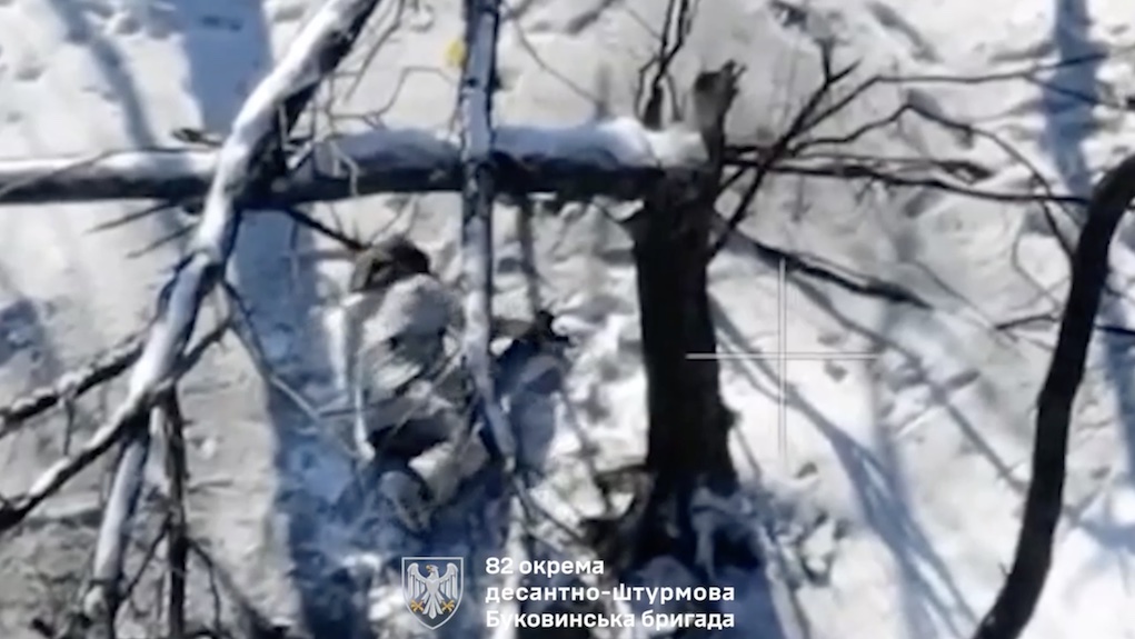 Russian is hiding from drone among snowy trees, grenade hits nearby. He first appears to try shoot himself in the heart, rolls over the ground for a while, then proceeds with giving himself a headshot