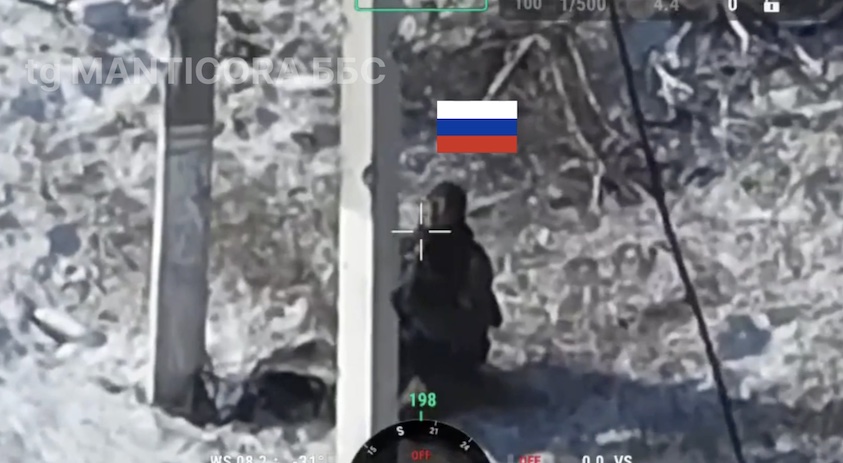 Russian with no helmet stands kneeled under concrete utility pole, briefly looks at the drone that is filming him and shoots himself