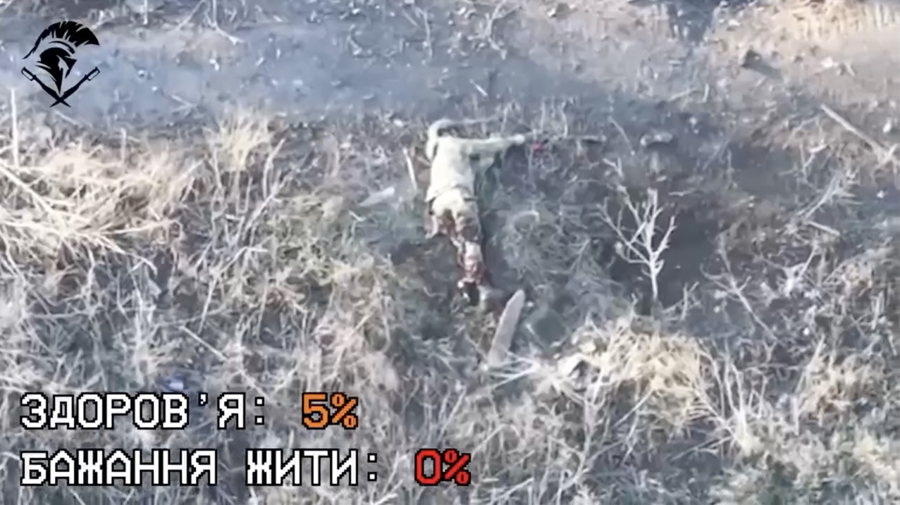 Russian soldier with severely wounded leg is seen lying on the ground, rolls on his side and shoots himself with AK