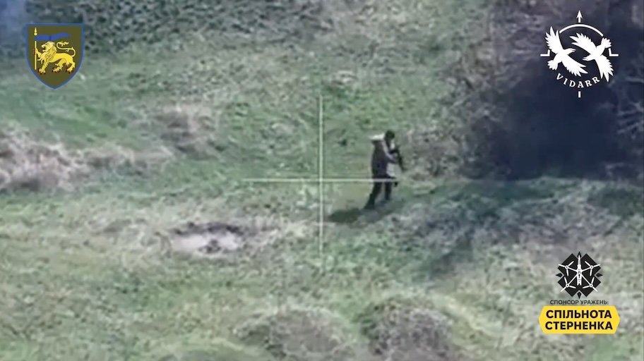 Russian soldier on a hill next to some kind of bushes is targeted by FPV drone. He rolls to avoid the blast, stands up, walks in a circle for a moment before shooting himself in the head while still walking