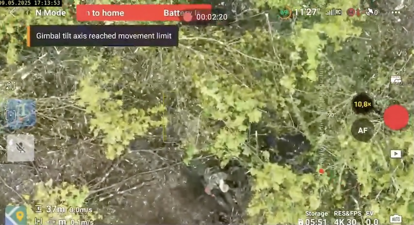 Russian soldier is seen straight from above shooting himself under the tree