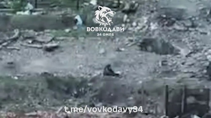 Russian is seen from afar sitting on the ground among rubbles and shooting himself