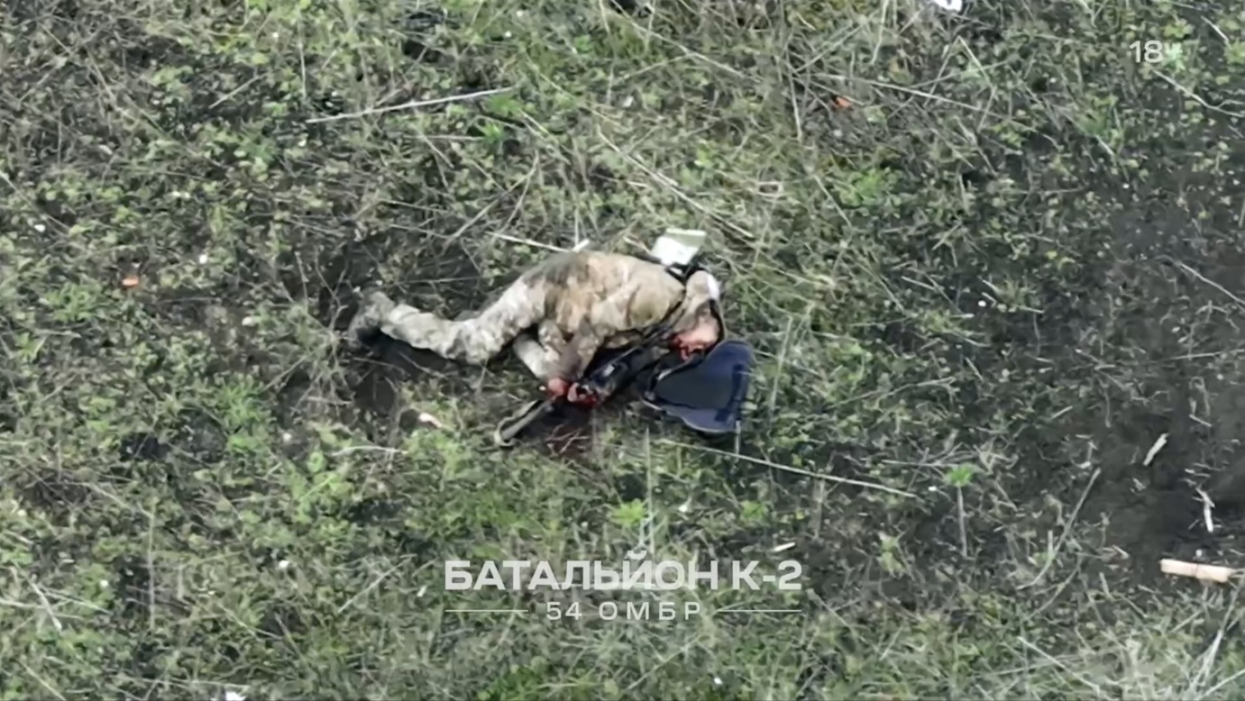 Russian is lying on the ground next to completely ruined house, apparently injured. He first aims AK at his chest, then makes several test shots, and after great deal of hesitation finally shoots himself by aiming around his chin. Camera zooms in on the aftermath