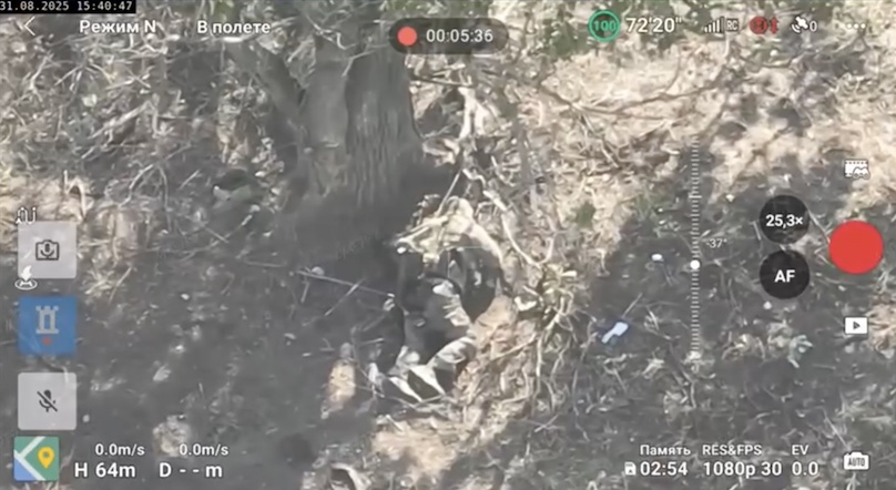 Russian soldier is seen lying face down under the tree, unclear if injured or not. He activates grenade with one hand, and puts it under his neck. Violent explosion turns him around