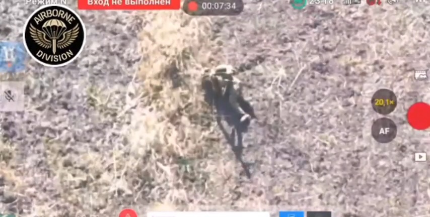 Laggy footage of wounded Russian soldier laying face down in a field. The camera zooms in as he rolls onto his side and shoots himself in the head