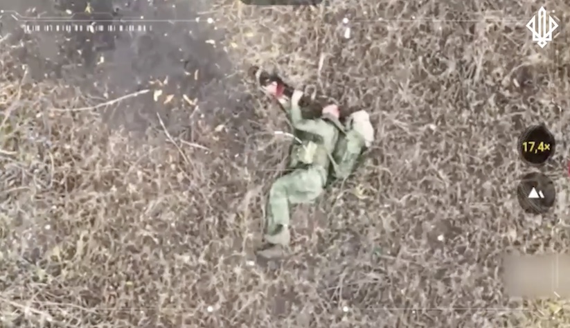 Russian with massive backpack lies on the ground on his side, swiftly points AK right at his forehead and shoots himself, another angle of the aftermath is featured shortly