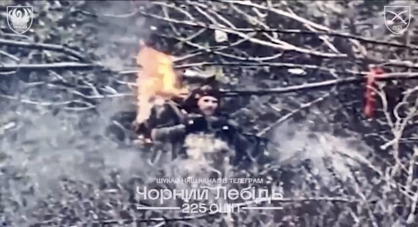 Russian is seen eating berries from bushes, receives FPV hit despite shooting back. He's now on the ground with his backpack on fire, takes grenade, puts it under his chin and detonates