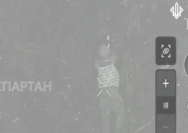 Russian soldier is seen right from above, he holds something in his hands, looks at the drone and shows he's unarmed. Is hit by a drone drop, falls on the ground. The thing in his hands turns out to be a grenade, which he puts under his neck and detonates