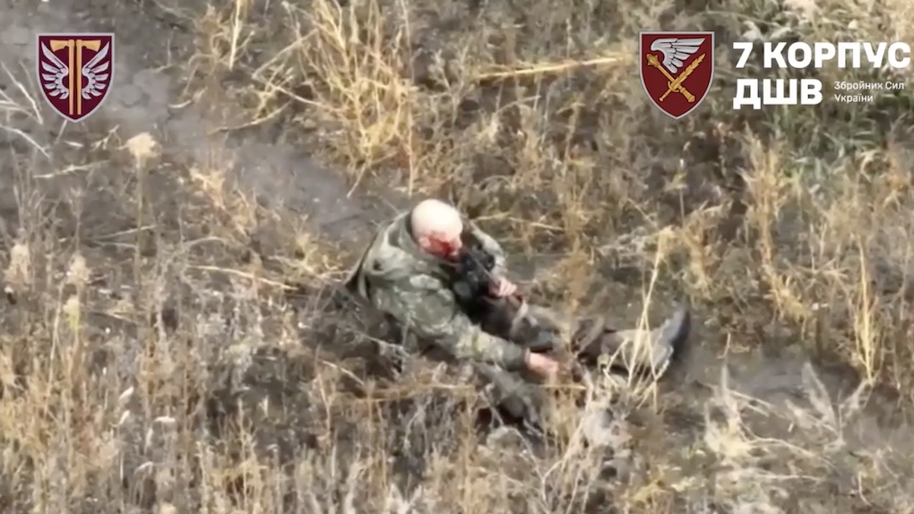Bald Russian walks casually along the trail besides what looks like tree line, receives drone drop, immediately grabs his AK, makes test shot while maintaining eye contact with drone operator, points it at his mouth and shoots himself