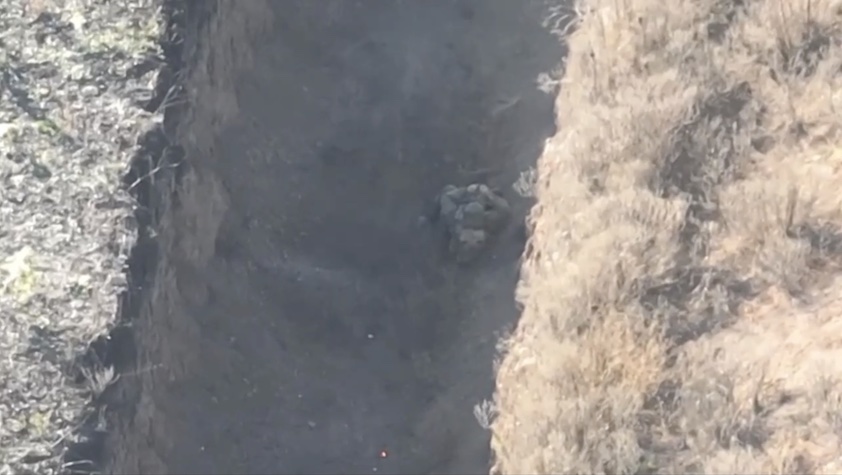 Zero context clip featuring Russian soldier lying on his back in a deep fresh ditch under some kind of attack, pulling the pin on his grenade and detonating it to his neck