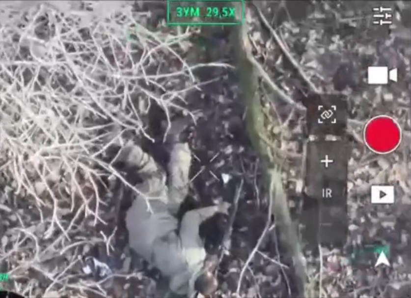 Russian soldier is seen from above shooting himself while lying on the ground besides fallen tree