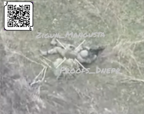 Fully equipped Russian lies on the ground i the open field, apparently unable to walk. He grabs his AK, points it at his face an pulls the trigger