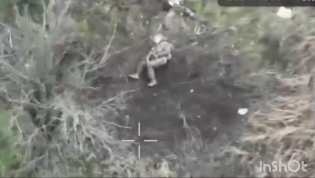 Quick cut of poor quality drone footage featuring Russian soldier shooting himself while lying on the ground, presumably injured