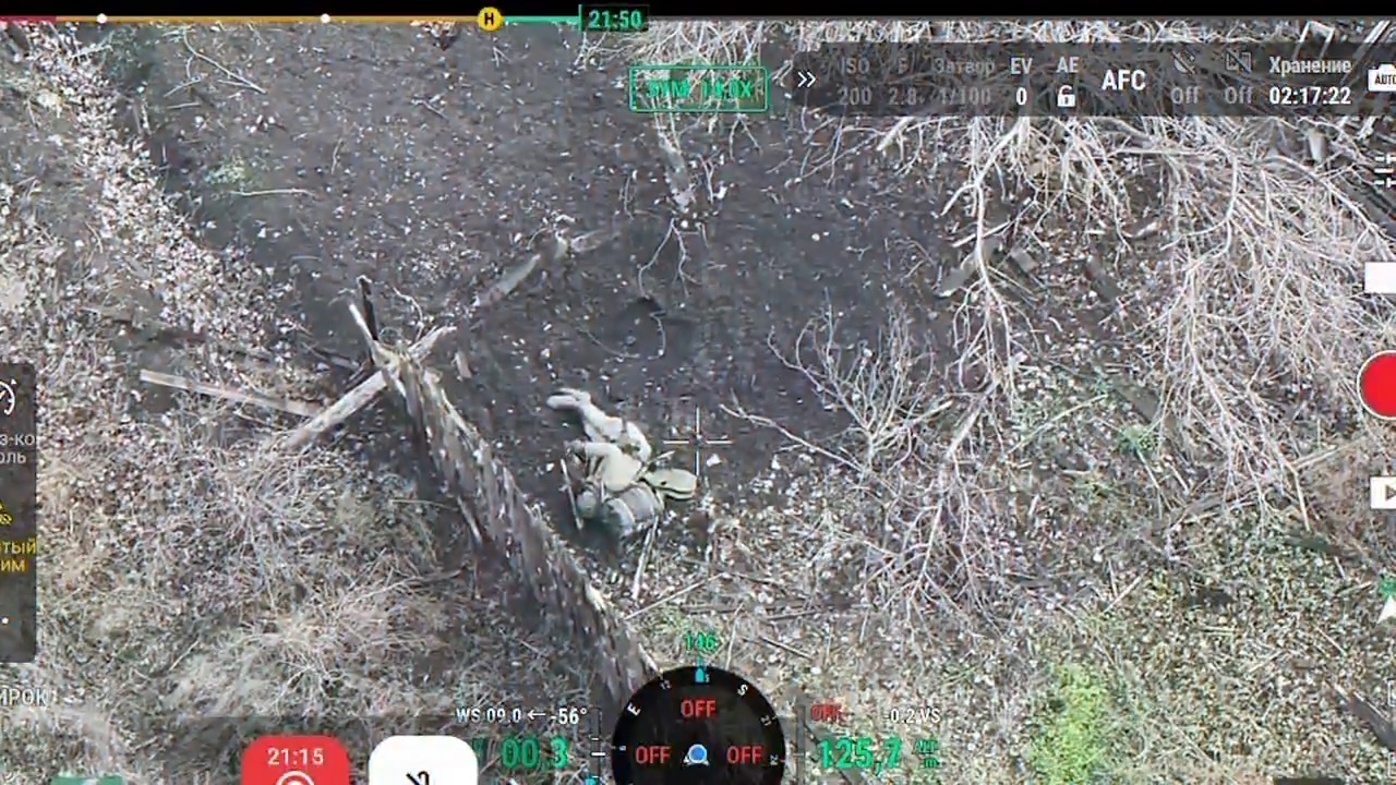 Wounded Russian soldier is seen lying on his side at the base of a small fence. He places grenade underneath his vest near his neck, it explodes shortly