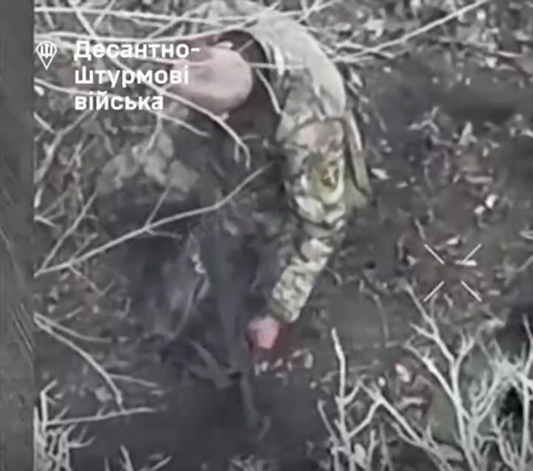 Quick cut of bald Russian soldier shooting himself swiftly in a temple while sitting on the ground