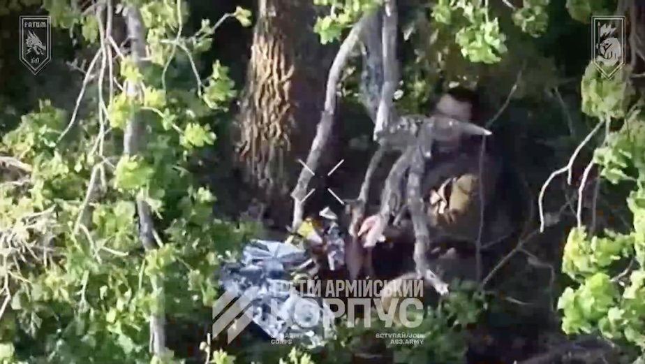 Russian with no helmet hides in the bushes while FPV is hunting him down. As it approaches, he appears to shoot himself