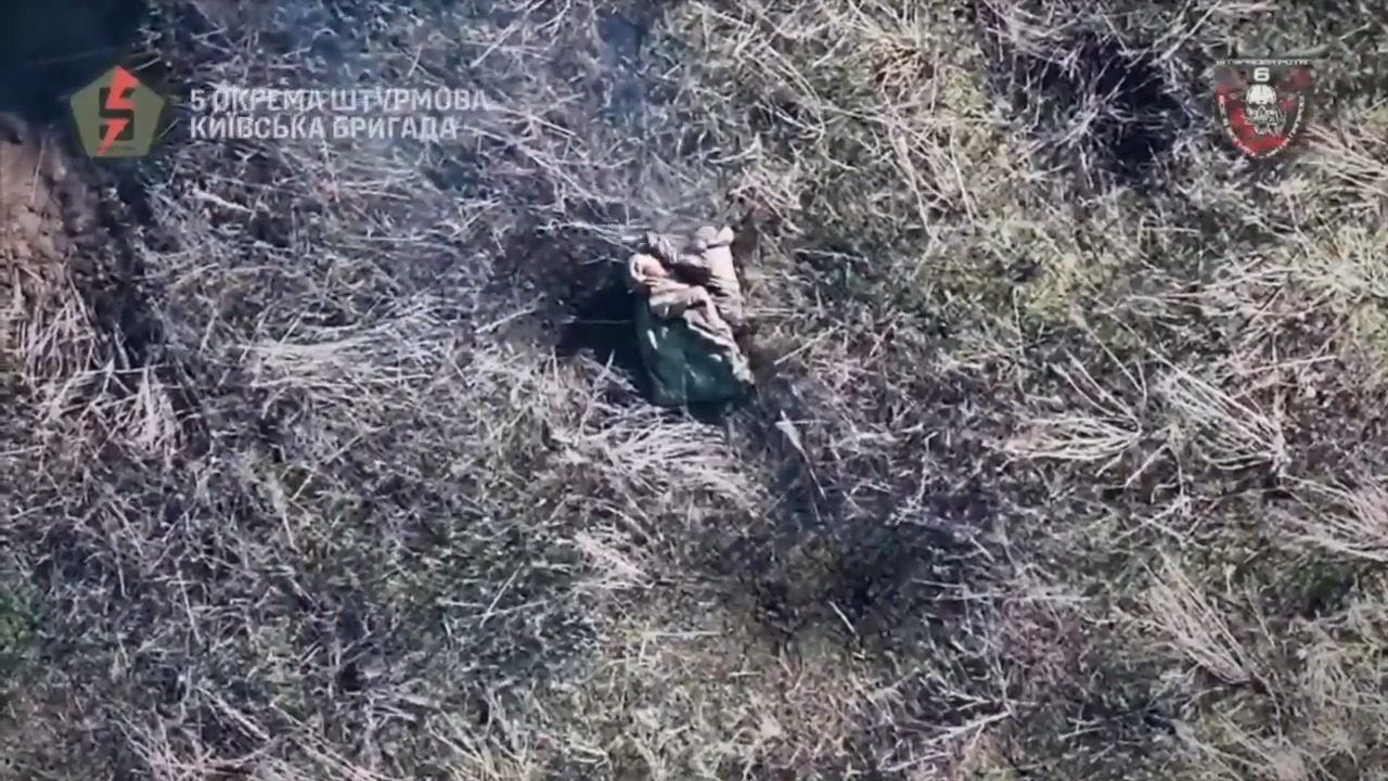 Russian soldier is struck by drone grenade. Looks like he is fumbling with something in his hands followed by an explosion