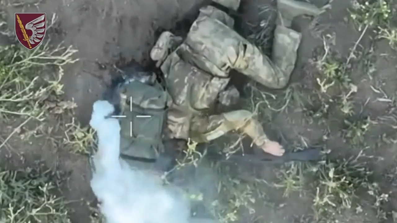 Russian is struck by drone dropped grenade, his backpack starts to emit a lot of smoke. Eventually shoots himself in the head